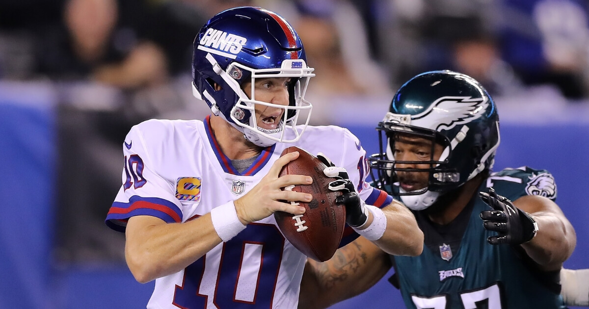 Eli Manning of the New York Giants scrambles before fumbling the ball from a hit by Michael Bennett of the Philadelphia Eagles during the first quarter of their game Thursday night at MetLife Stadium in East Rutherford, New Jersey.