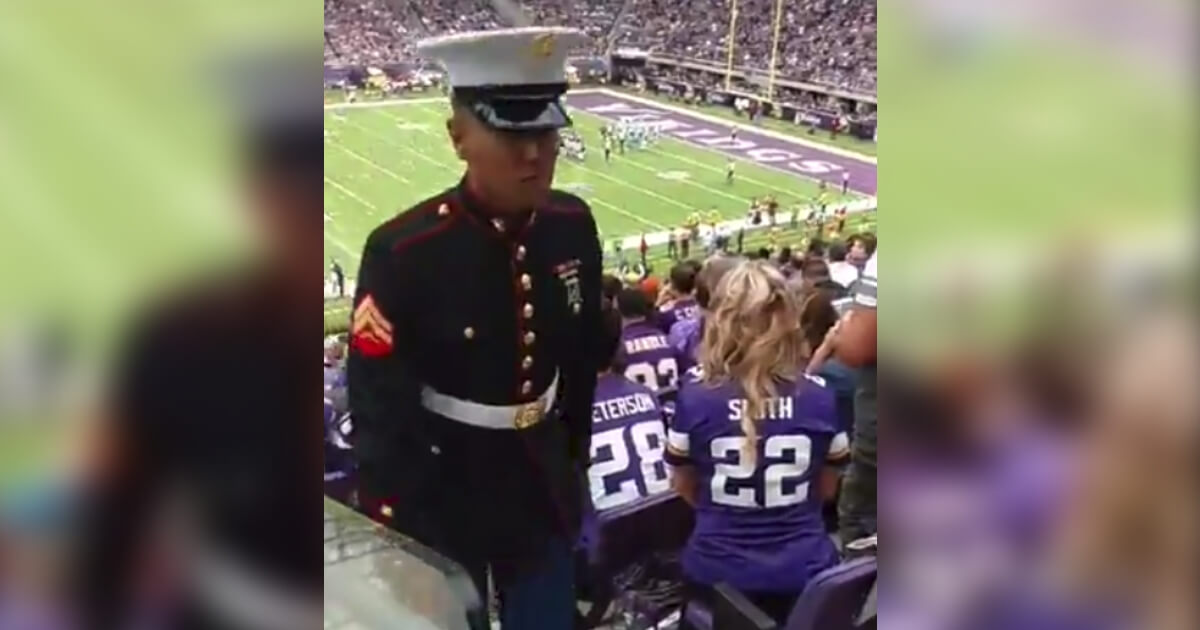 Two Marines in full dress uniform keep watch over an empty seat at the Minnesota Vikings' stadium.
