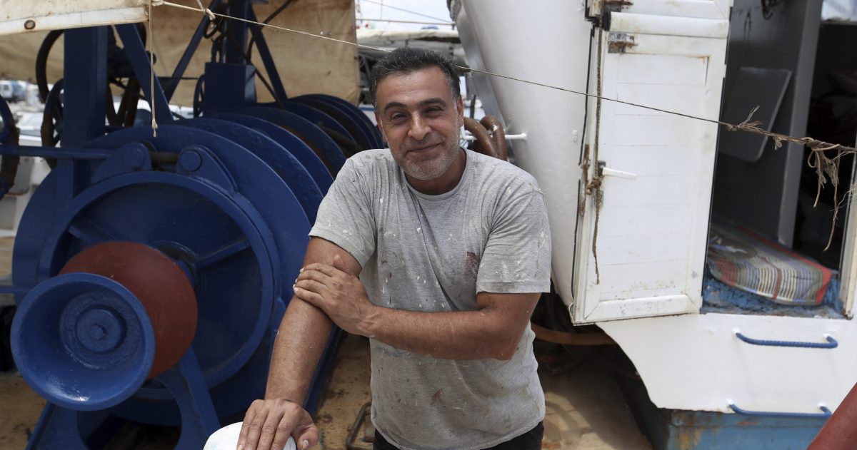 Egyptian fisherman Halil Tawefik poses on his fishing boat in Rafina port, east of Athens, Wednesday, July 25, 2018. Tawefik says the cries for help pierced the thick, choking smoke as his fishing boat plucked young and old from the sea where they sought refuge from the flames that tore through the seaside report of Rafina.