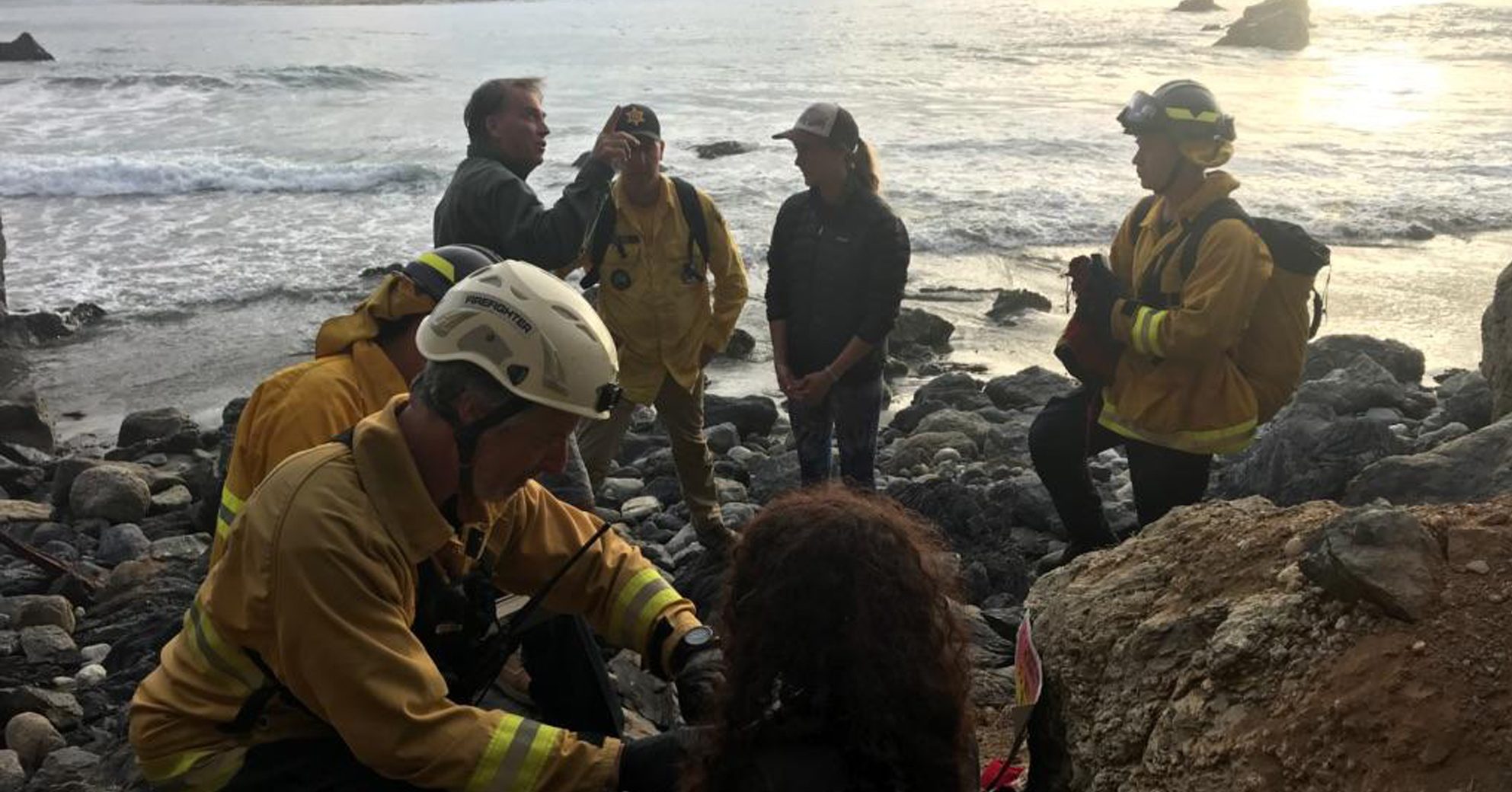 In this Friday, July 13, 2018, photo posted on the Monterey County, Calif., Sheriff's Office Twitter feed, authorities tend to Angela Hernandez, foreground center, after she was rescued, in Morro Bay, Calif. Authorities say a couple on a camping trip came upon Hernandez, from Oregon, who had been missing since July 6, after her car went over a cliff in coastal California. (