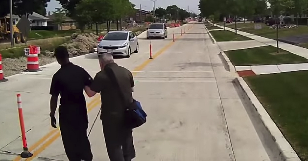 A bus driver stops traffic to help a blind man cross the street.