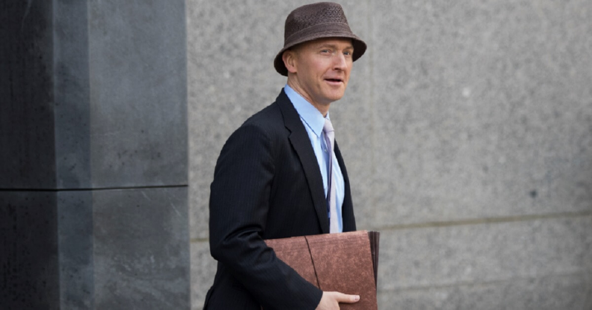 Carter Page wearing a hat and carrying a briefcase outsde a court building.