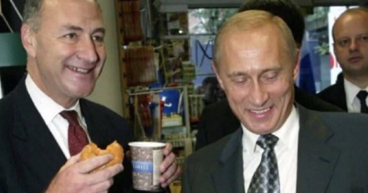 Chuck Schumer, left, holding coffee and a donut. Putin, on the right, is laughing.