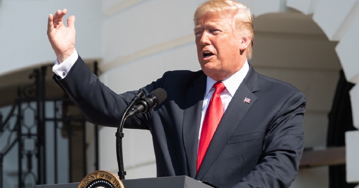 President Donald Trump gestures while speaking at a lectern.