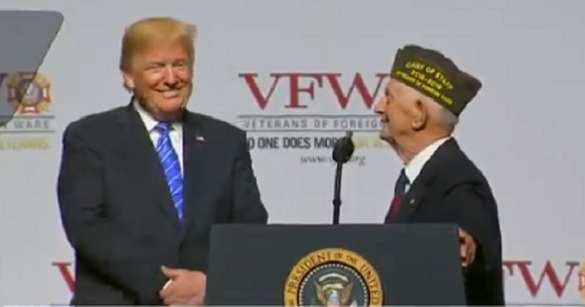 Donald Trump grinning with elderly veteran onstage