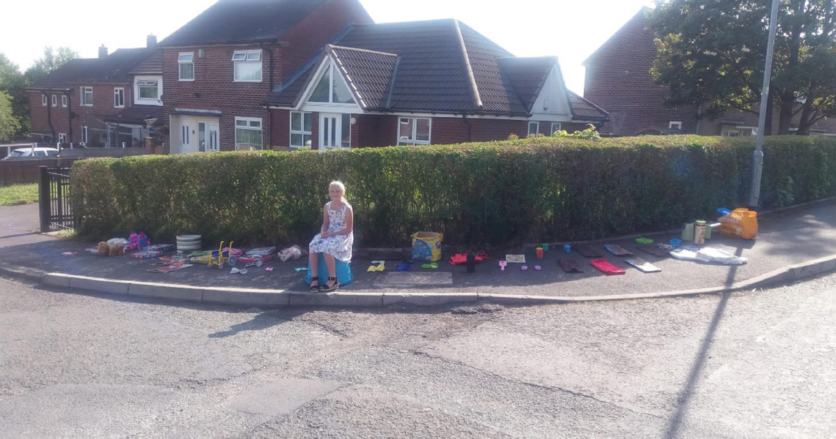 A little girl sells toys on the side of the road