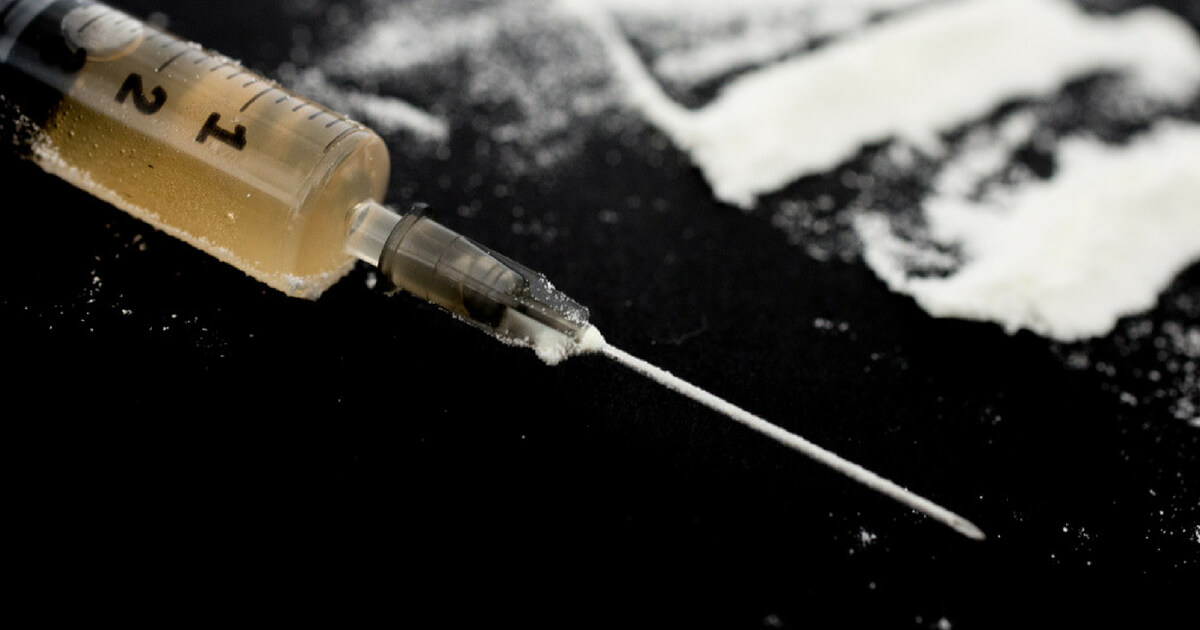 A syringe on a table near a powdery substance