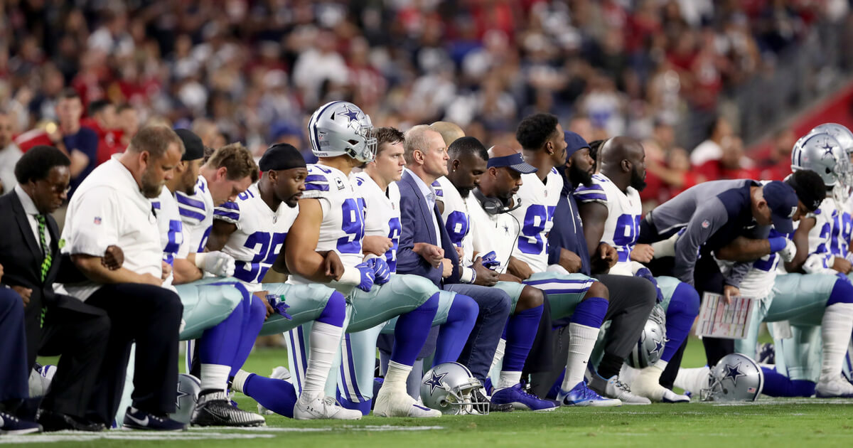 Members of the Dallas Cowboys link arms and kneel during the national anthem before the start of the NFL game against the Arizona Cardinals at the University of Phoenix Stadium on September 25, 2017, in Glendale, Arizona.