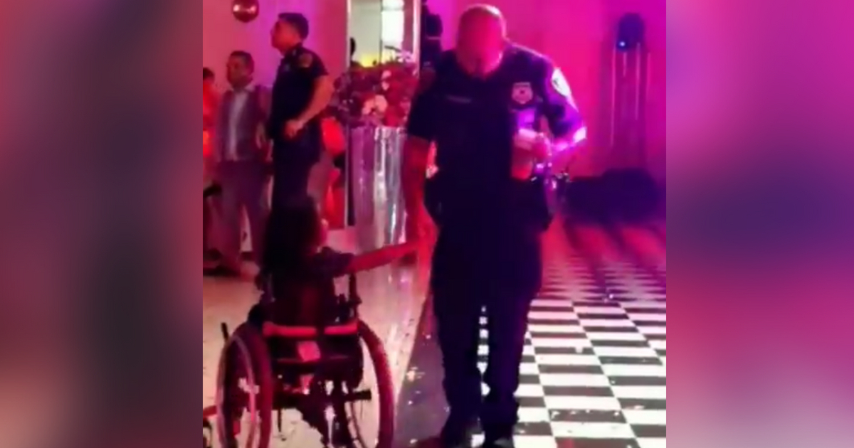 Police officer dances with girl in wheelchair.