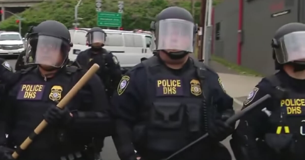 Police stand in riot gear outside the ICE headquarters in Portland, Oregon