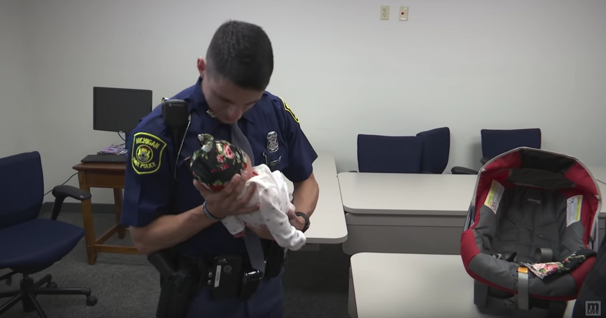 State trooper looks down at the baby he saved.