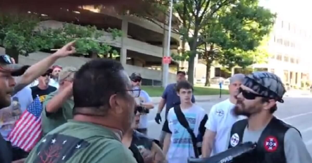 Group of people confronting a man in sunglasses.