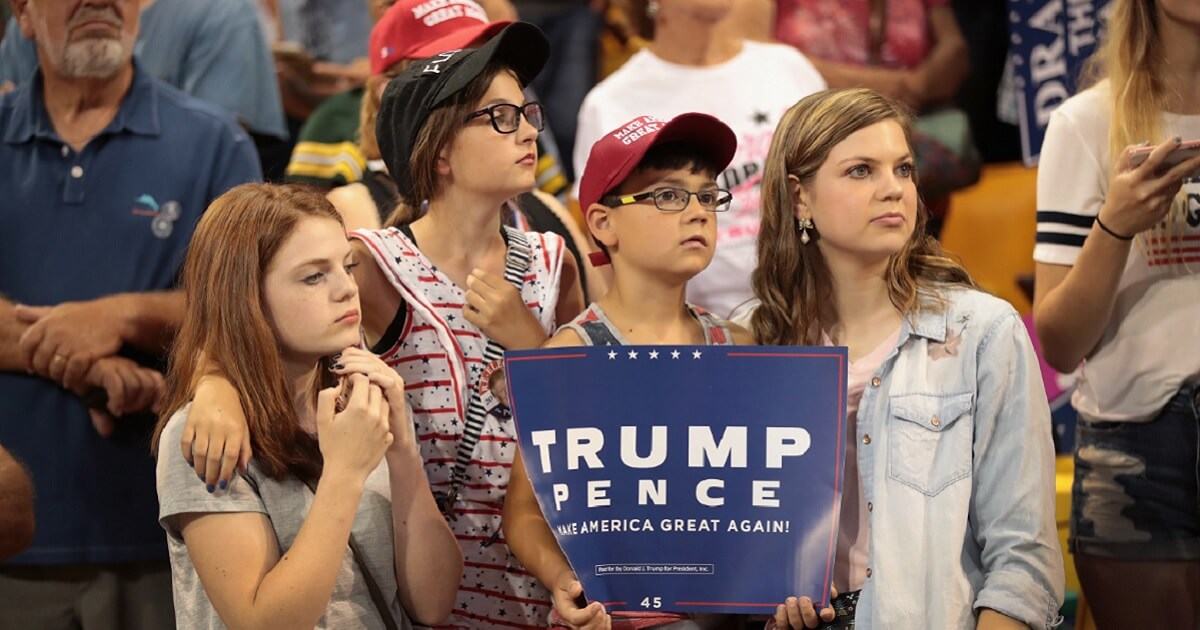 Three girls and a boy who holds a Trump/Pence sign.