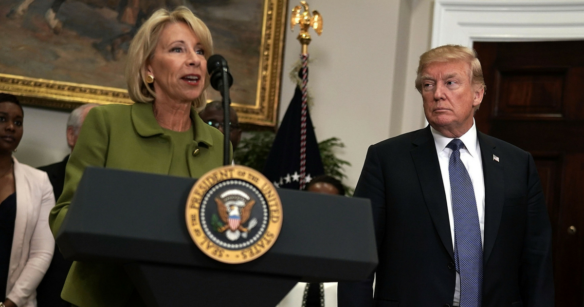Secretary of Education Betsy DeVos (L) speaks as President Donald Trump listens during an announcement in the Roosevelt Room