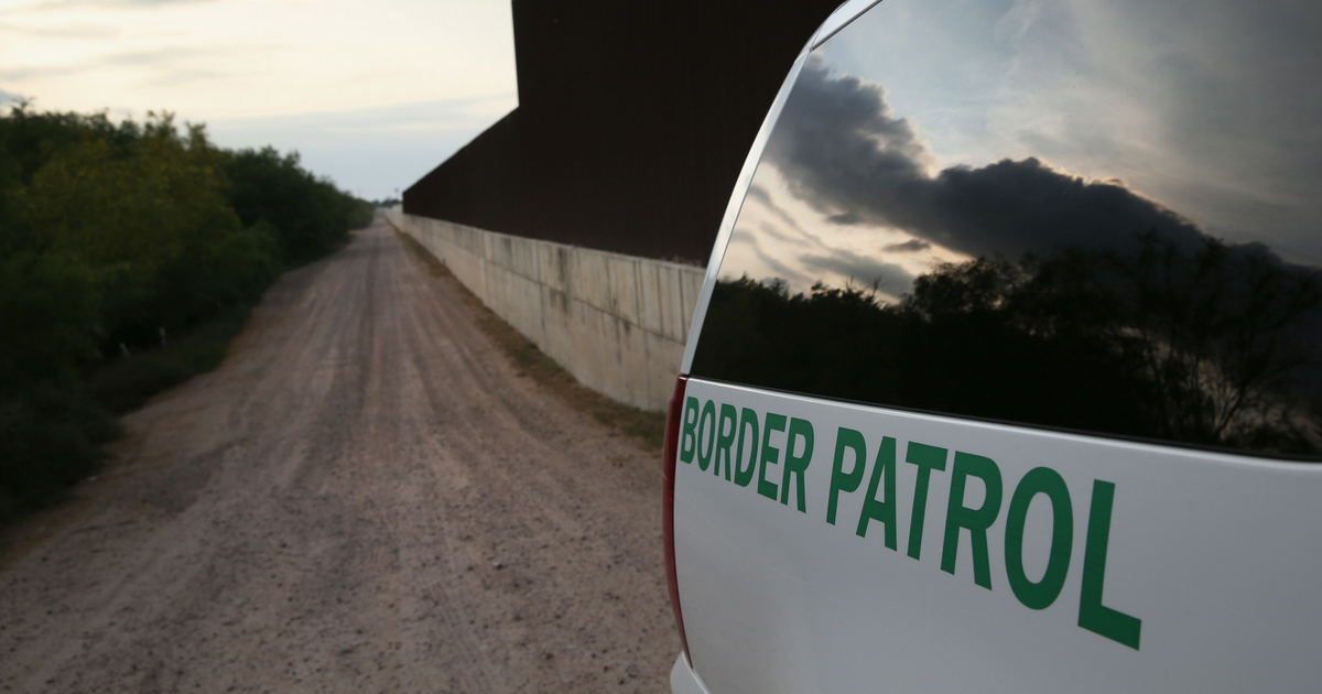 Border Patrol car drives next to border fence along the Rio Grade