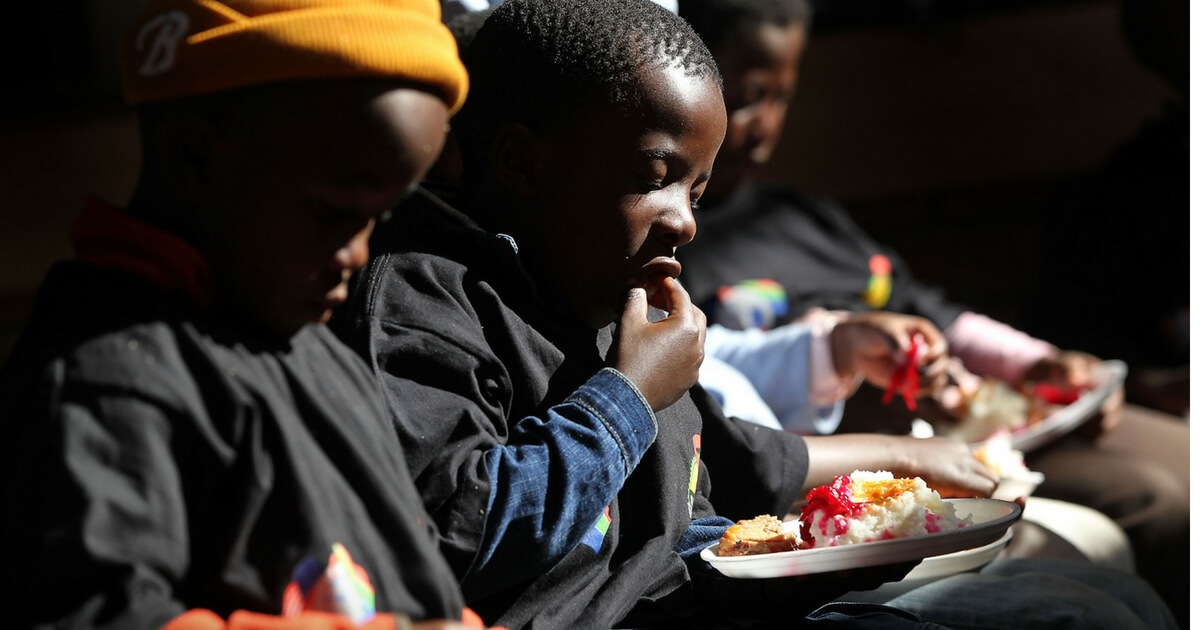 Youth eat a free lunch while at a camp run by the South African Business Coalition
