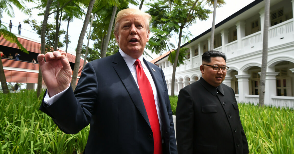US President Donald Trump speaks to the media as he walks with North Korea's leader Kim Jong Un (R) during a break in talks at their historic US-North Korea summit