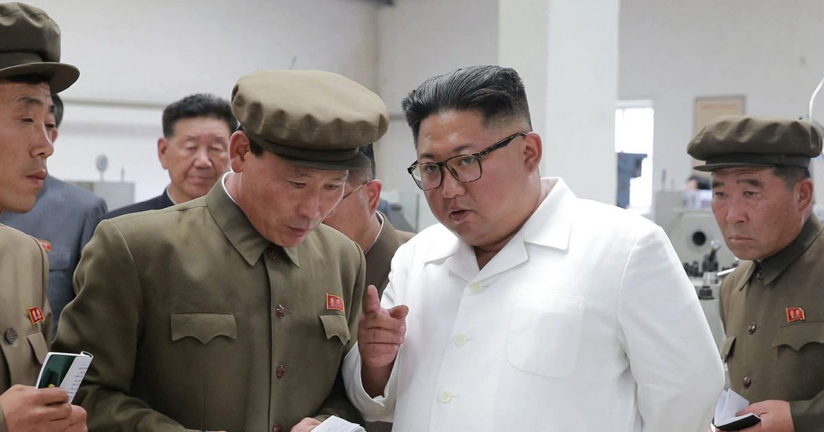 Kim Jong Un, center, speaks during a visit to a machine factory.