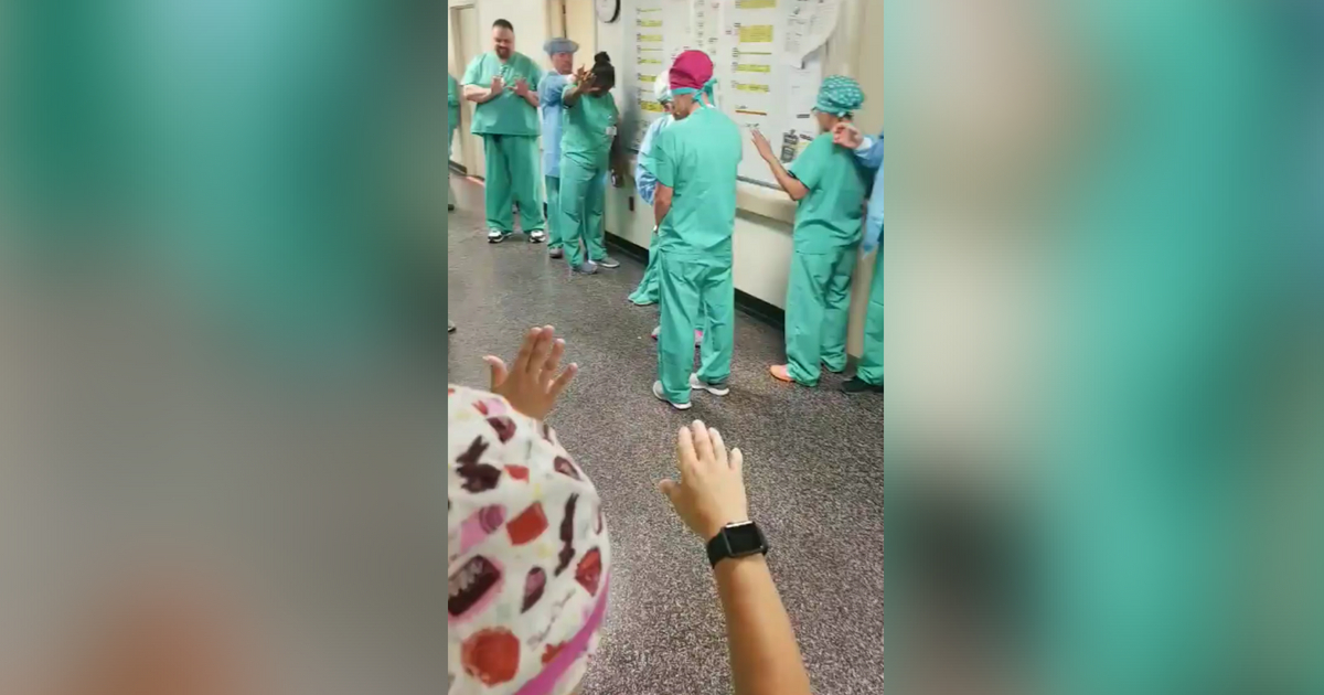 Nurses dressed in green scrubs pray for hospital and coworkers.