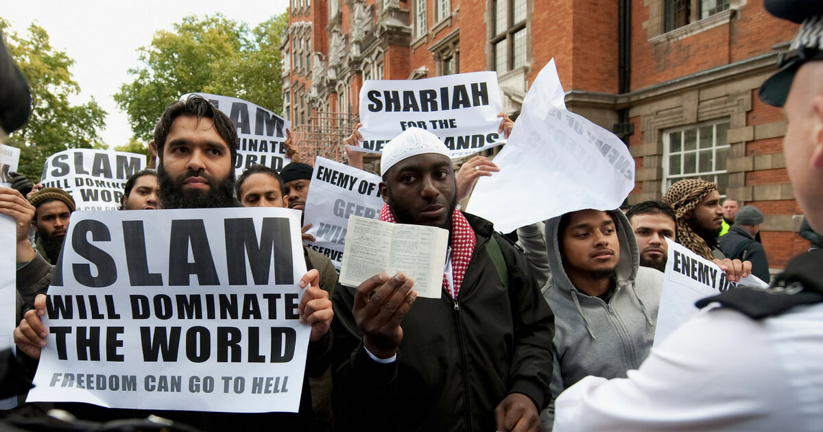Muslim protestors hold placards outside a press conference