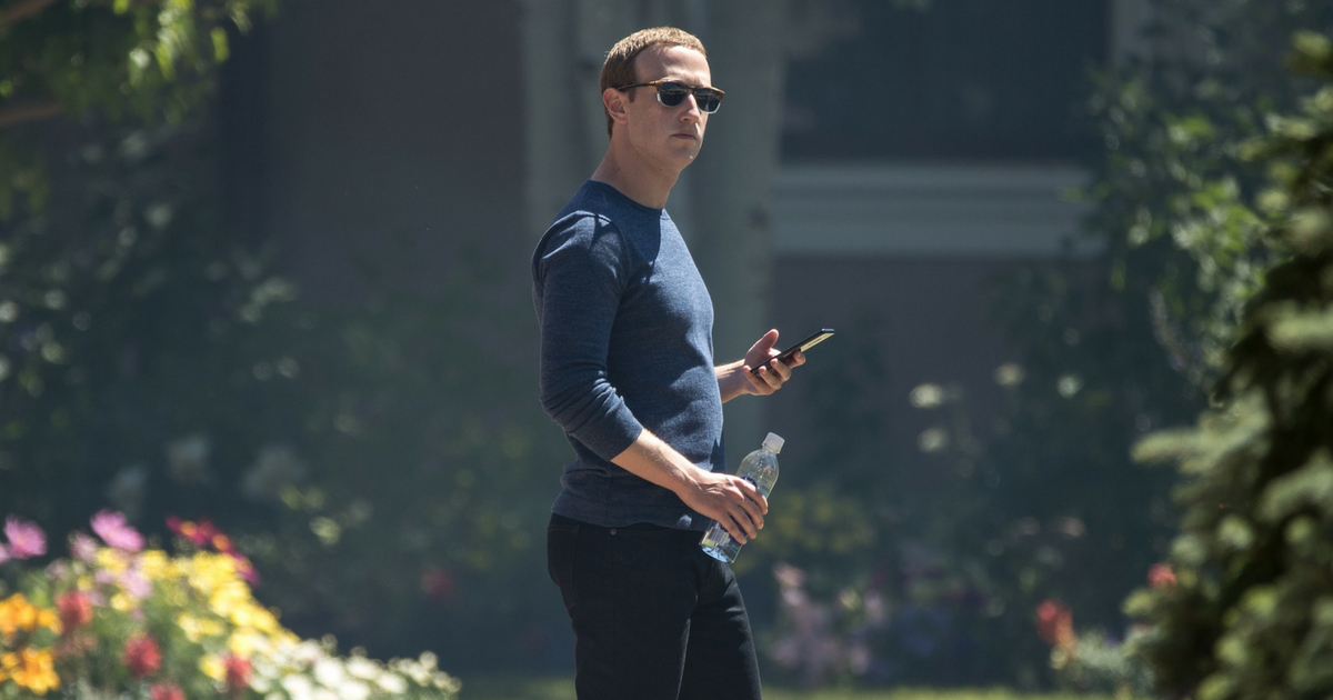 Mark Zuckerberg stands with his phone outside