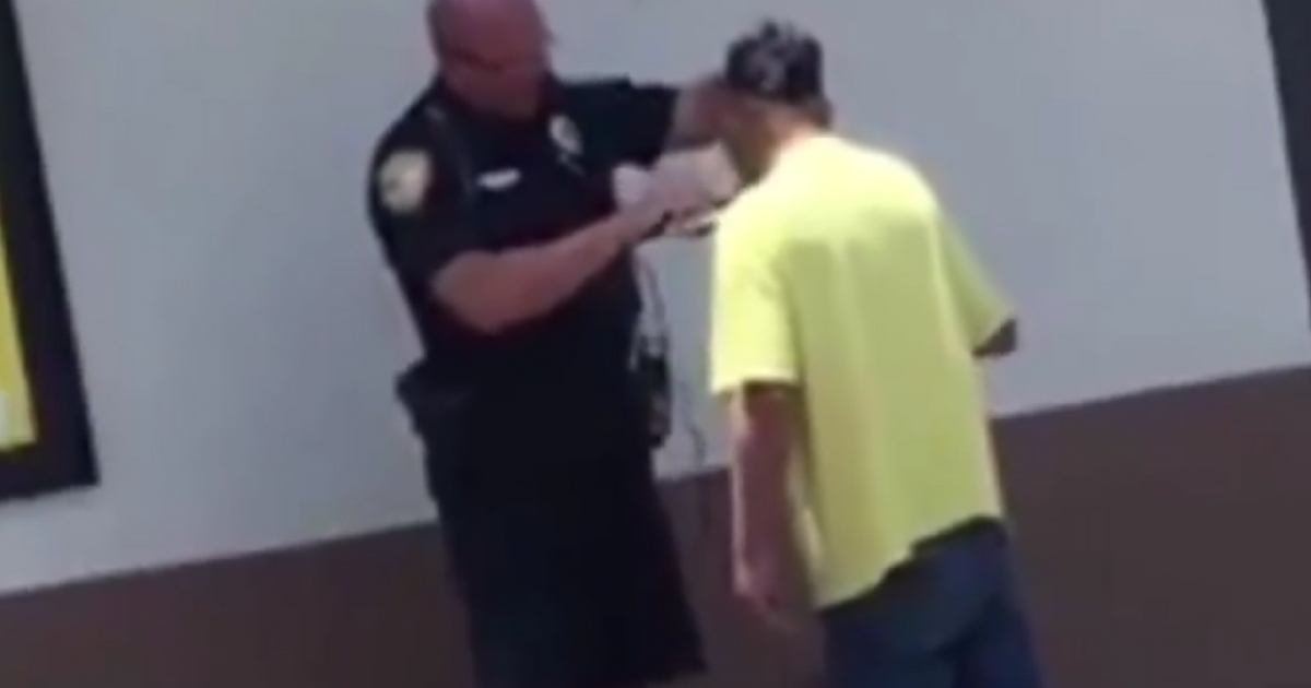 A police officer helps a homeless man shave.