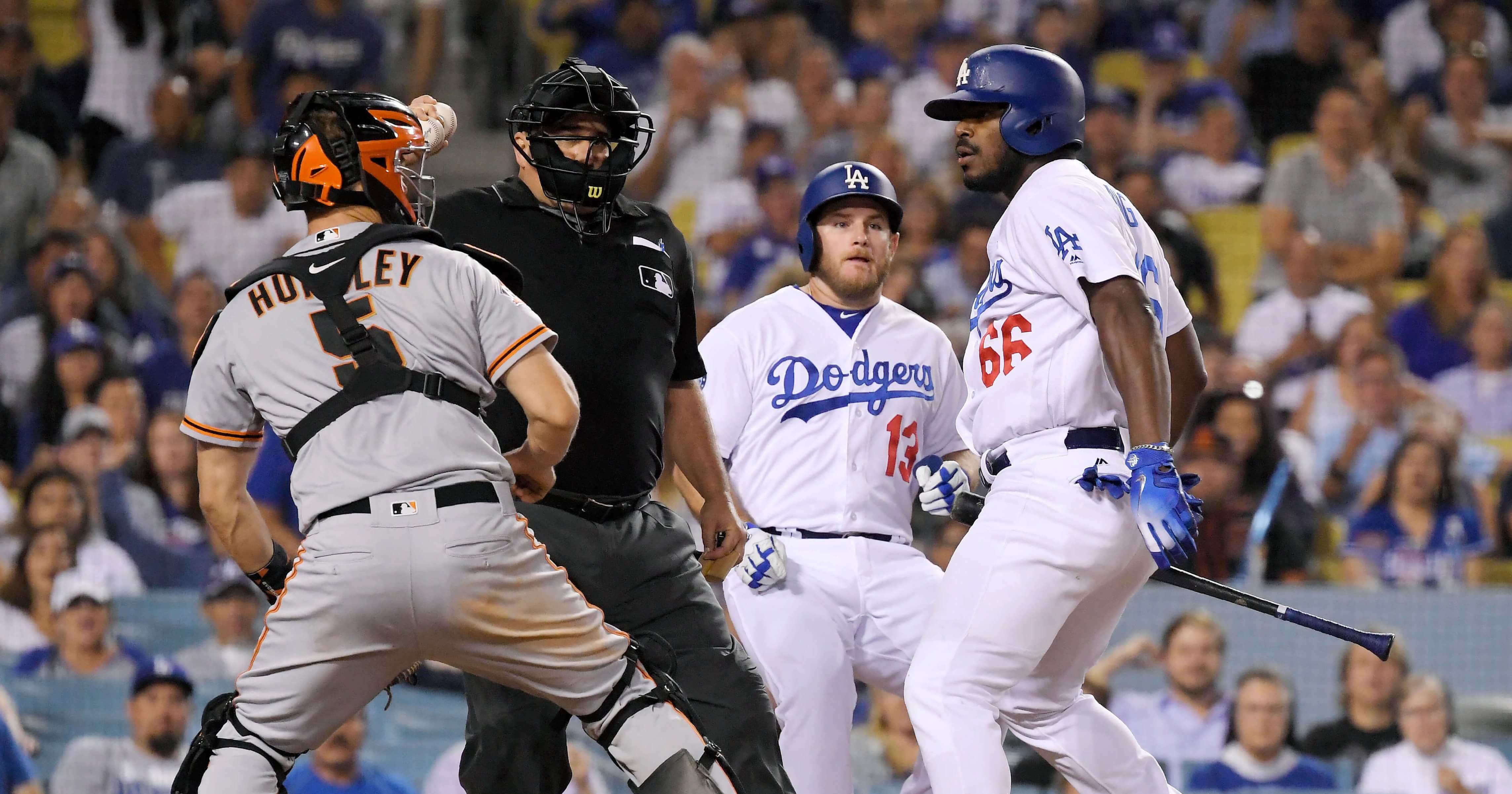 San Francisco Giants catcher Nick Hundley, left, reacts to being shoved by Los Angeles Dodgers' Yasiel Puig, right, as they argue while home plate umpire Eric Cooper, second from left, gets between them and Max Muncy runs in during the seventh inning of a baseball game, Tuesday, Aug. 14, 2018, in Los Angeles.