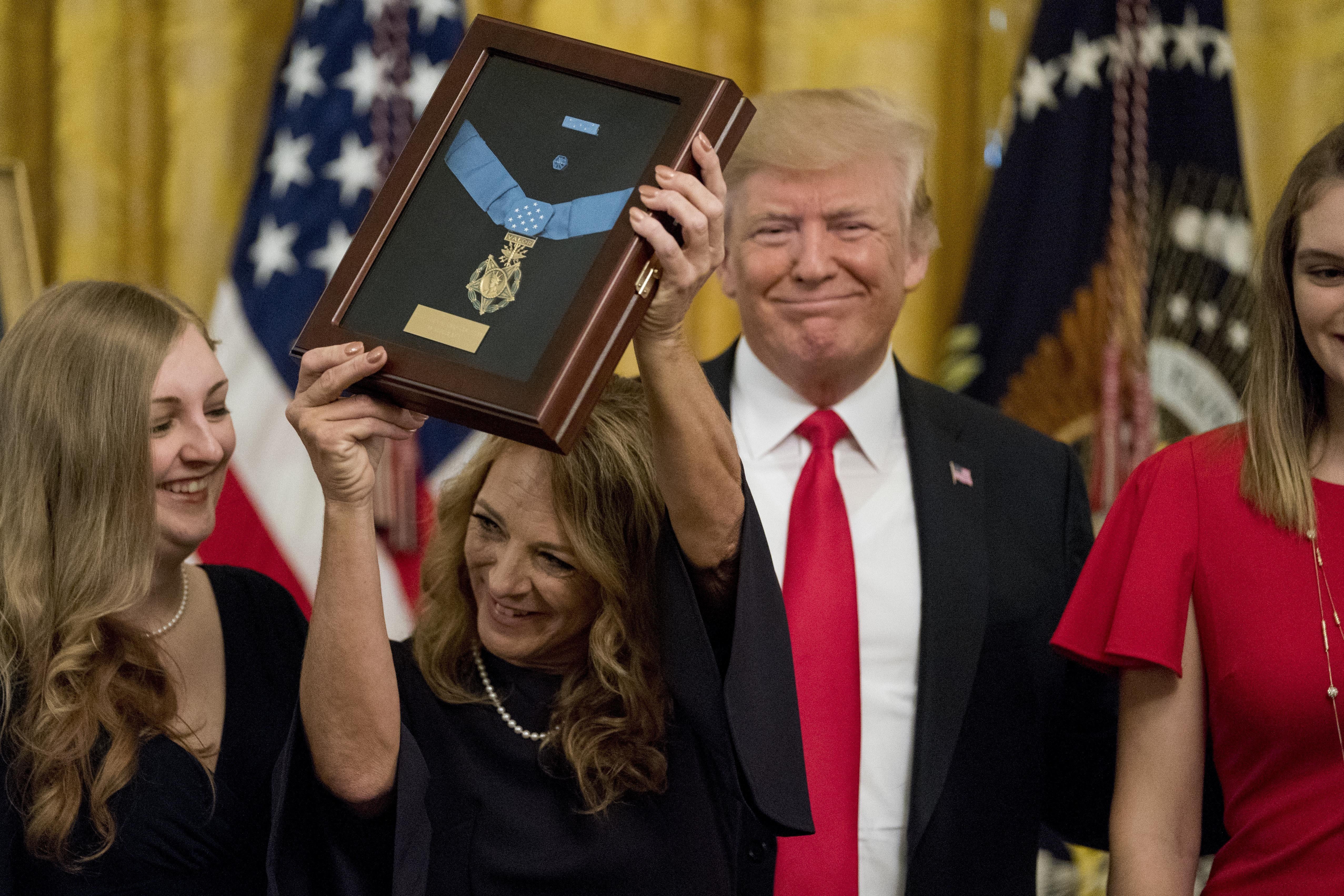 Valerie Nessel, second from left, accompanied by family members, accepts the Medal of Honor from President Donald Trump, second from right, for her husband Air Force Tech. Sgt. John A. Chapman, posthumously for conspicuous gallantry during a ceremony in the East Room of the White House in Washington on Wednesday.