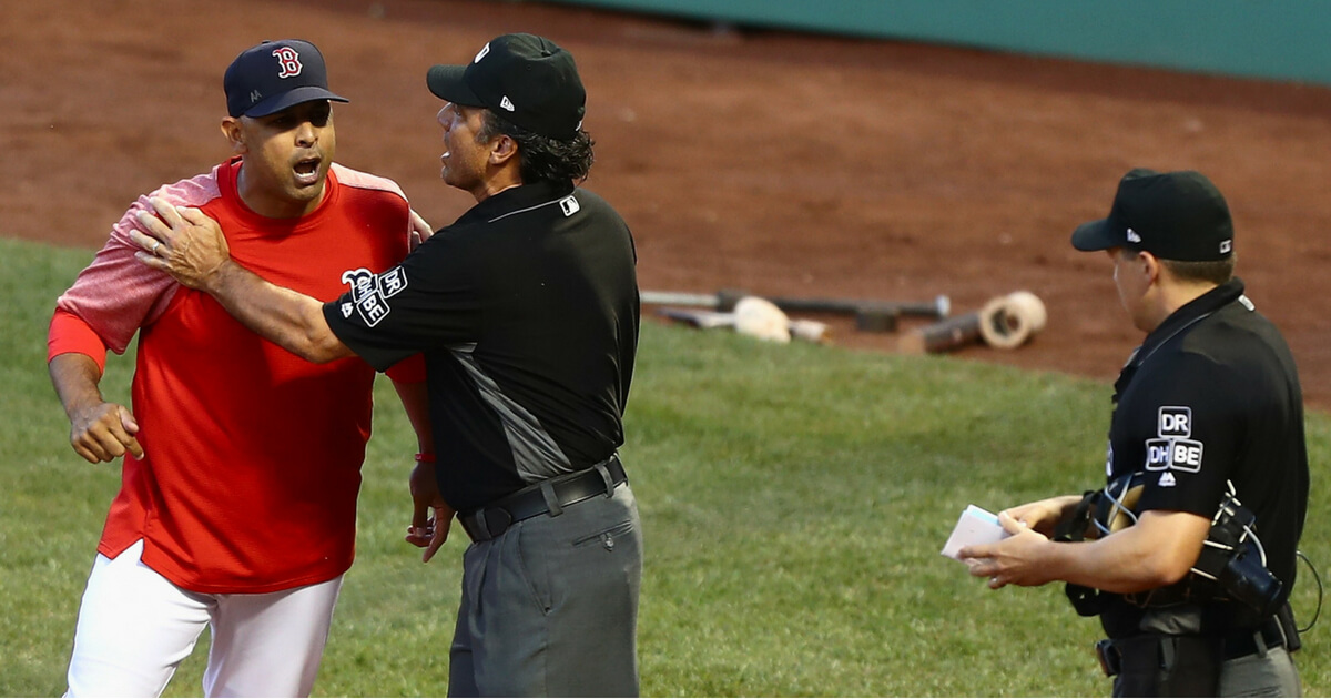 First base umpire Phil Cuzzi #10 holds back Alex Cora #20 of the Boston Red Sox from home plate umpire Adam Hamari #78 after being ejected in the bottom of the first inning against the New York Yankees at Fenway Park on August 3, 2018 in Boston.