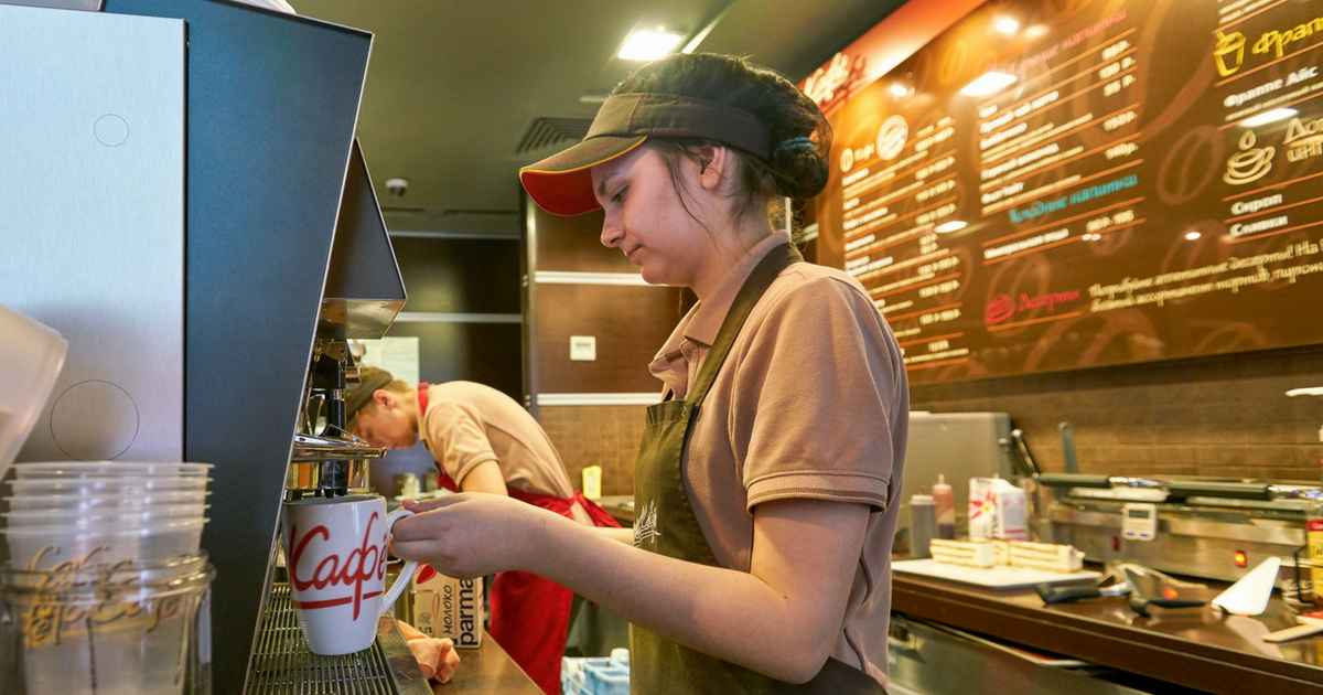 A woman prepares coffee at a fast-food restaurant