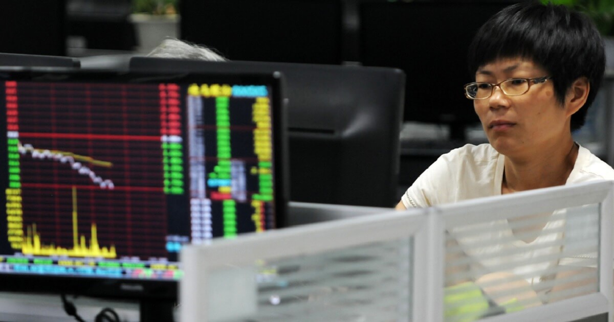 A Chinese man stares at computer screens on a stock exchange