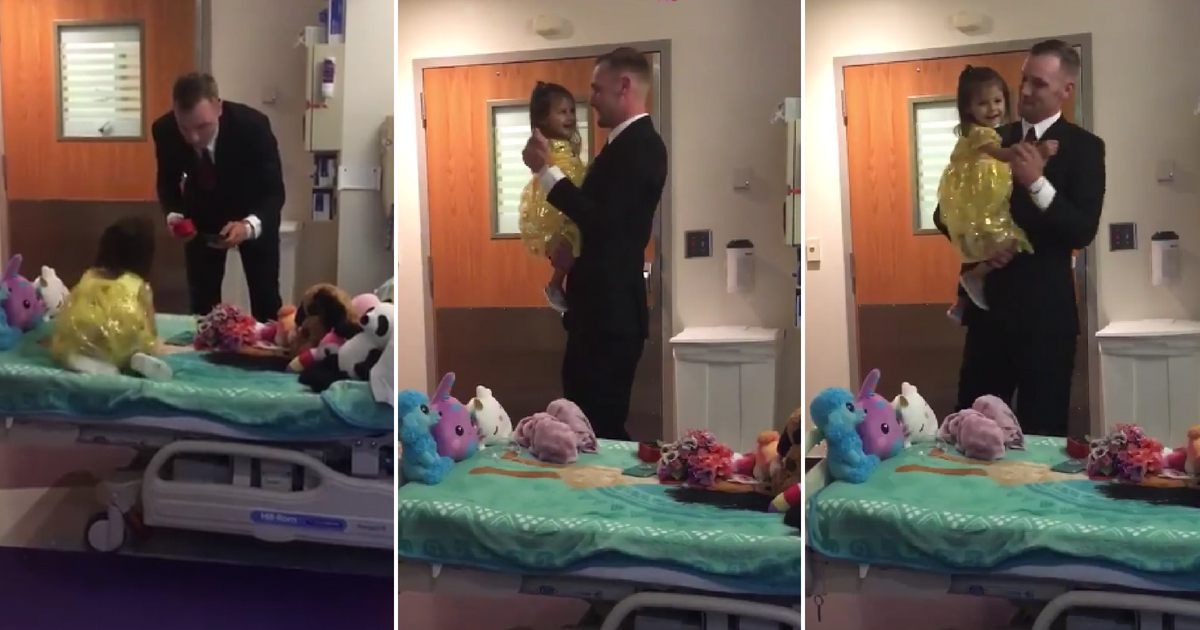 A dad in a suit dancing with his daughter in a yellow dress in the hospital.
