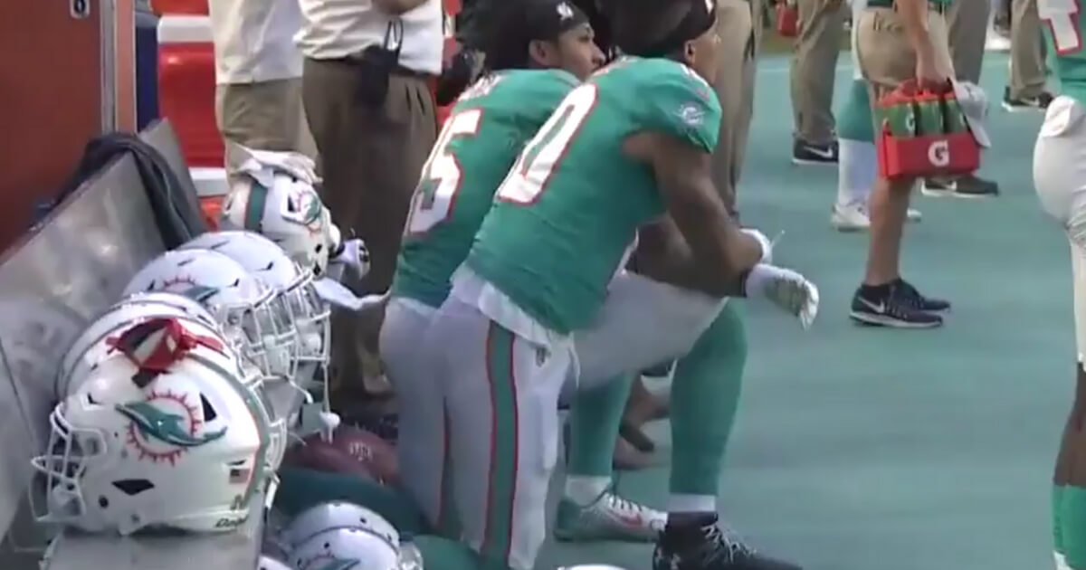 Two Miami Dolphins players kneel during the national anthem prior to a preseason game
