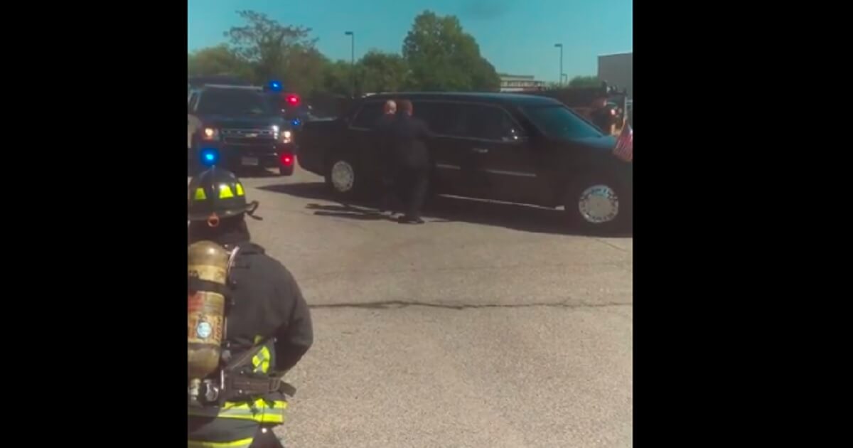 A firefighter waits as two men open a limousine door.