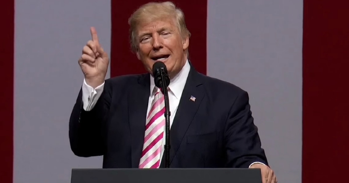 Trump at podium with index finger in the air.
