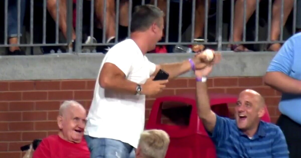 A fan is congratulated after making a one-handed catch of a fly ball while talking on the phone during the Phillies-Red Sox game.