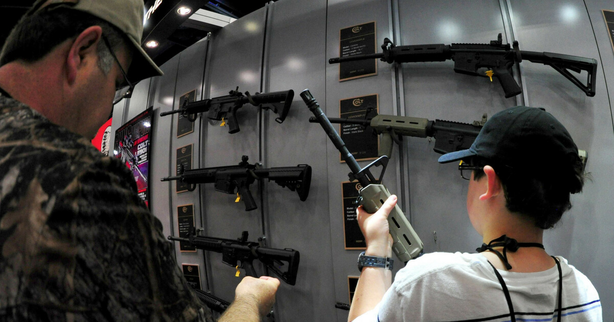 A father and his son look at Colt semiautomatic rifles at the NRA Convention on May 4, 2013 in Houston.