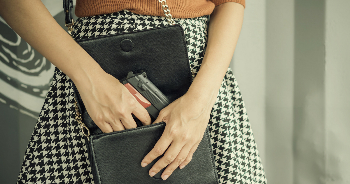 A woman pulls a gun from her purse.