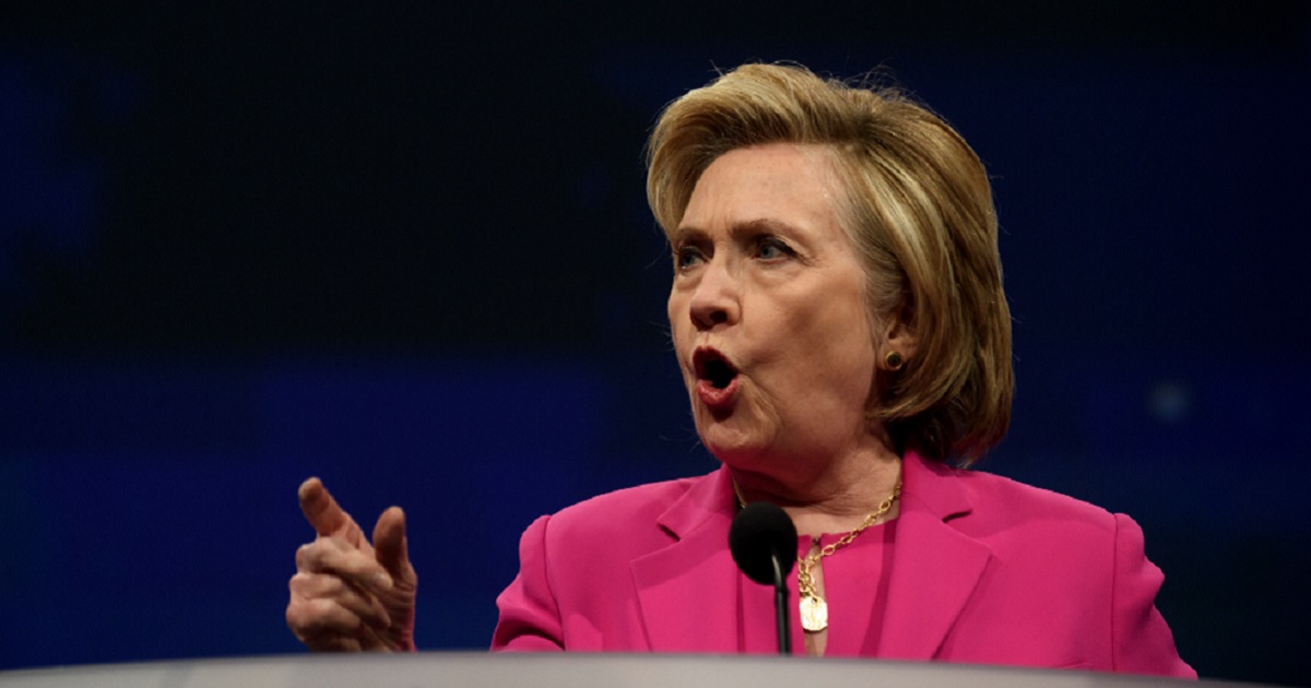 Hillary Clinton points from a podium while making a speech.
