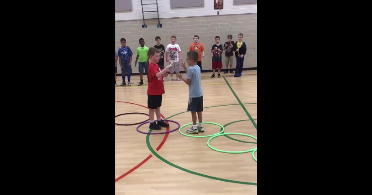 Two boys play rock, paper, scissors while standing in hoops.