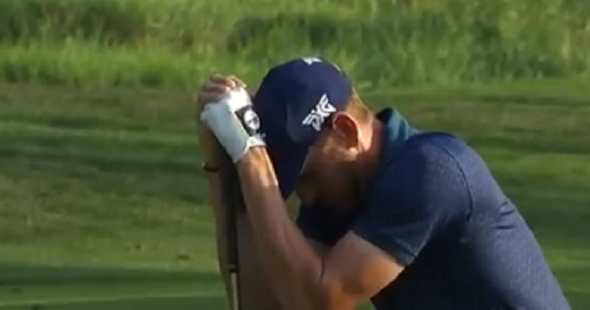 Golfer crouches with his head in his arms.