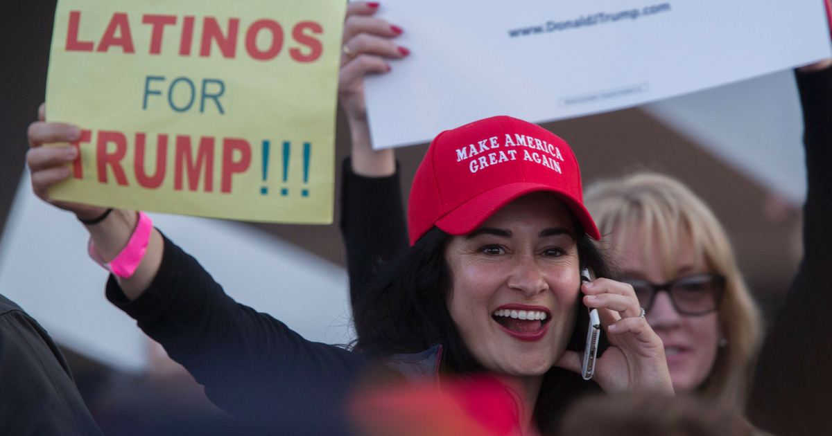 A woman hoods a sign expressing Latino support for Republican presidential candidate Donald Trump at his campaign rally at the Orange County Fair and Event Center, April 28, 2016, in Costa Mesa, California.