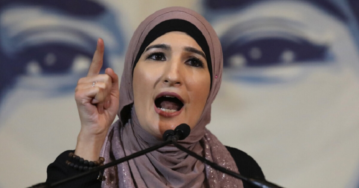 Woman in head scarf speaks into microphone