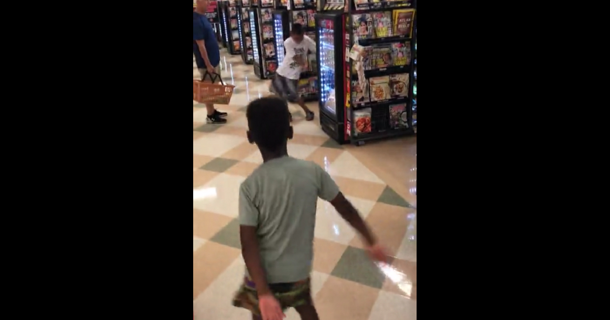 Two little boys have a dance-off in the checkout line.