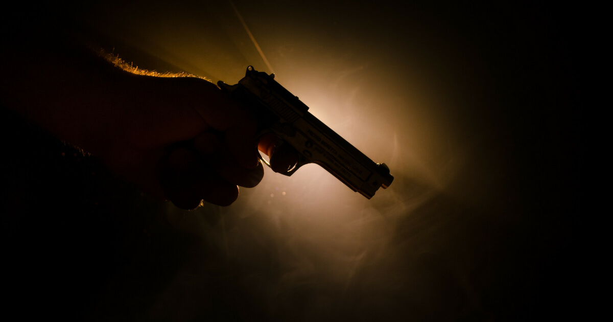 Male hand holding gun on black background with smoke ( yellow orange red white ) colored back lights