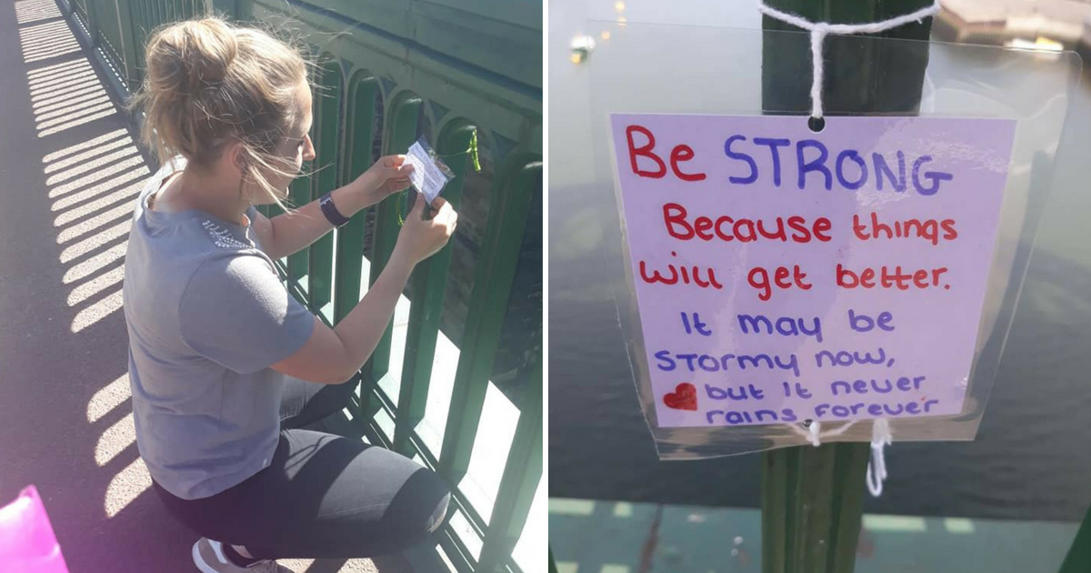 A young woman ties signs to a bridge.