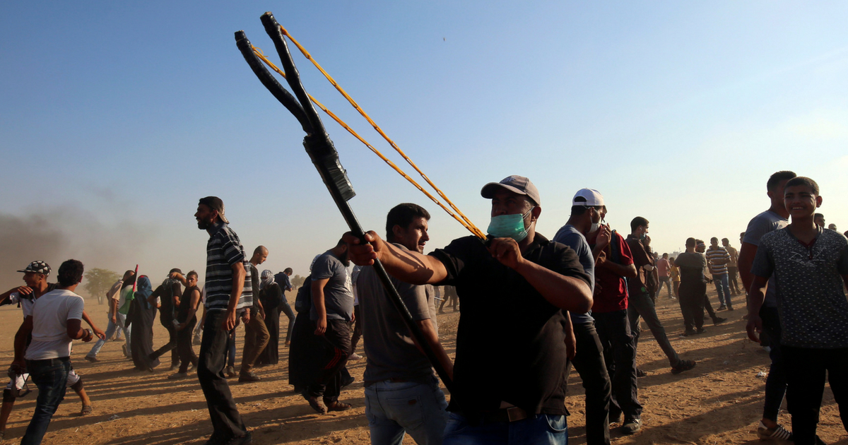 A Palestinian protester uses a slingshot to throw stones at Isrealis during a demonstration at the Israel-Gaza border, east of Khan Yunis in the southern Gaza Strip on Aug. 24, 2018.