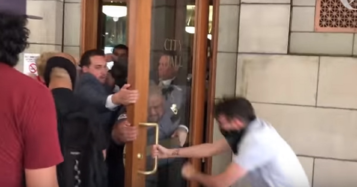 Masked man holds door open while City Hall workers try to close i.