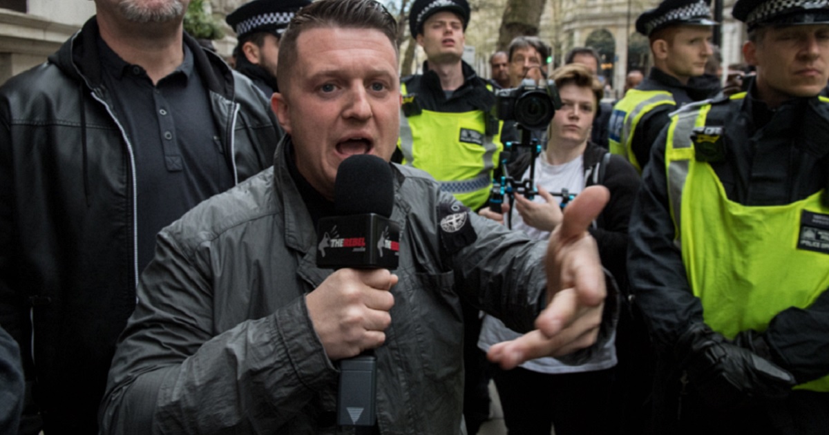 Man holding microphone in street crowd.