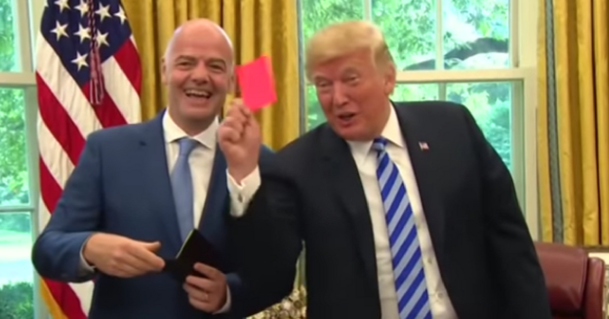 President Donald Trump accepts a red card from FIFA president Gianni Infantino and points it at the media